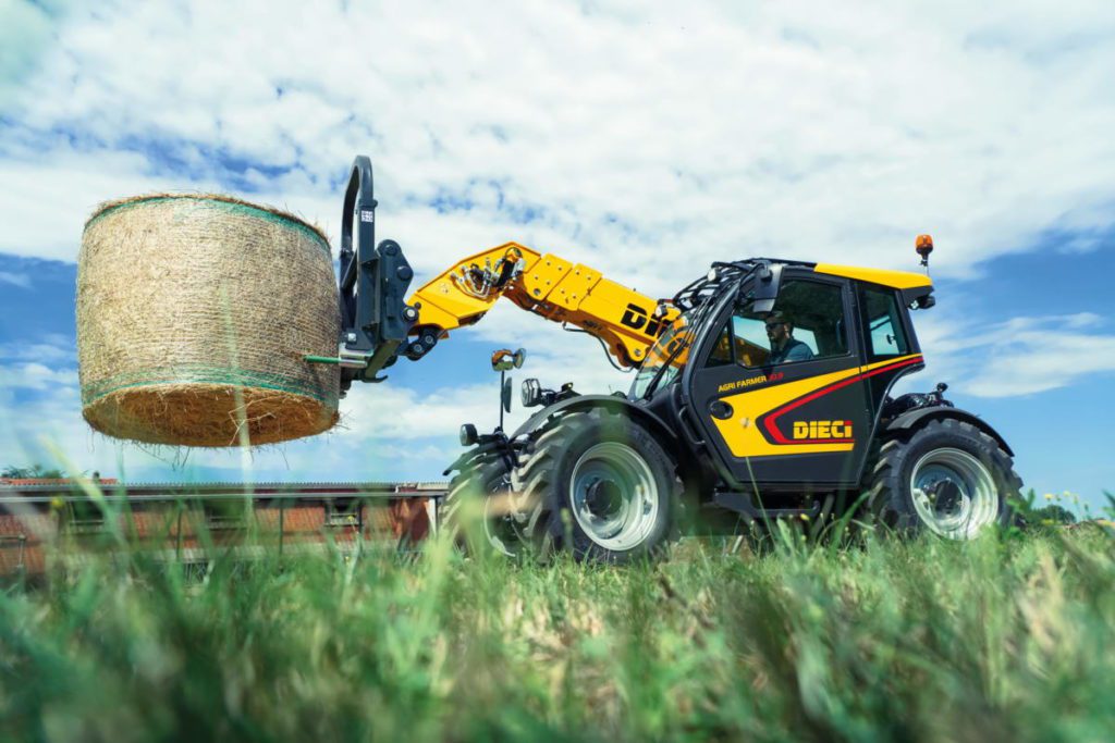 A yellow and black DIECI tractor with a load of hay.