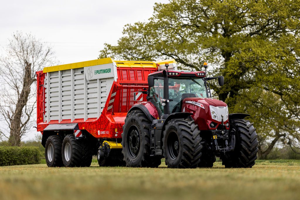 A red tractor with a trailer in a field.